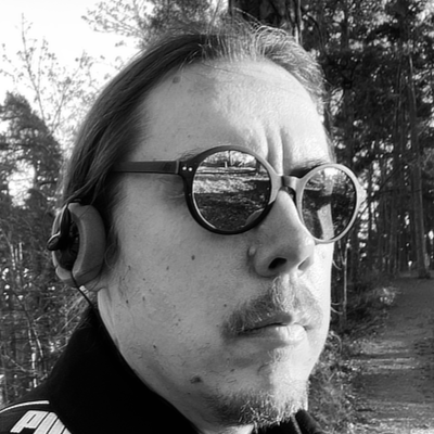 a white guy wearing sunglasses and headphones in the forest